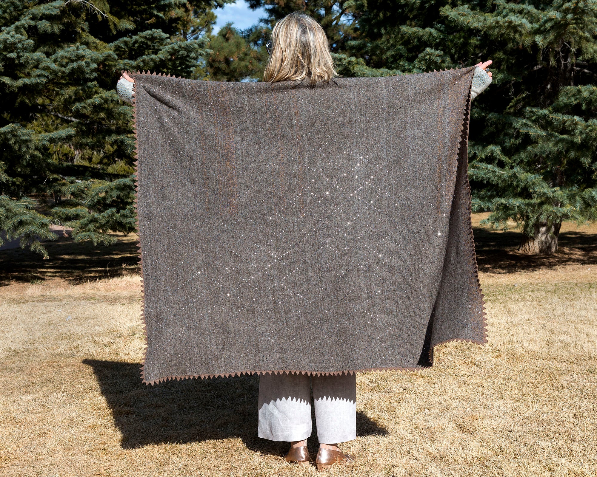 Woman holding up Taupe Merino Boucle Knitted Throw. editorial-image