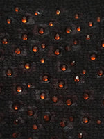 Black cashmere fabric swatch embellished with red crystals.