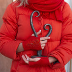 Close up of a woman wearing a Cardinal colored Tissue Weight Shawl and Cropped Stingray Gloves, holding a heart sculpture. editorial-image